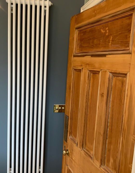 tall white designer radiator against blue wall